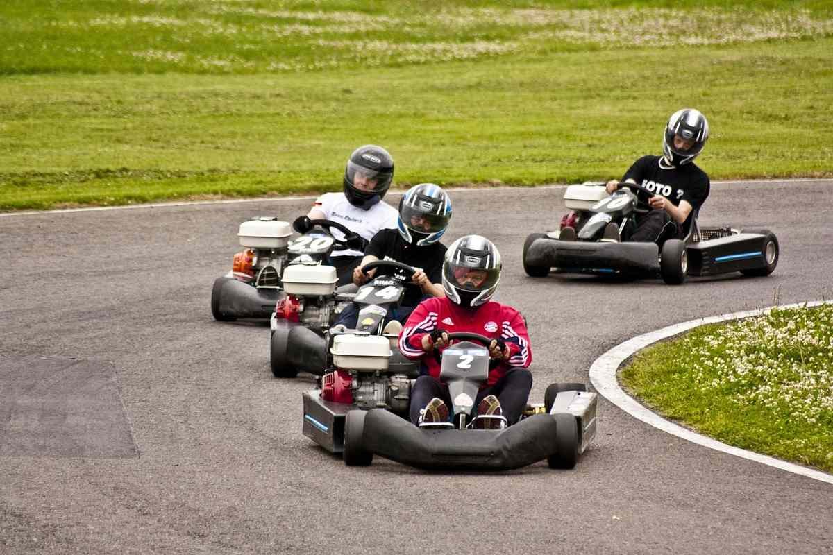 Quatre enfants en kart participant à une course d'endurance sur circuit avec virage Quatre enfants en kart participant à une course d'endurance sur circuit avec virage