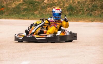 Pilote en combinaison jaune conduisant un kart jaune et orange sur piste asphaltée