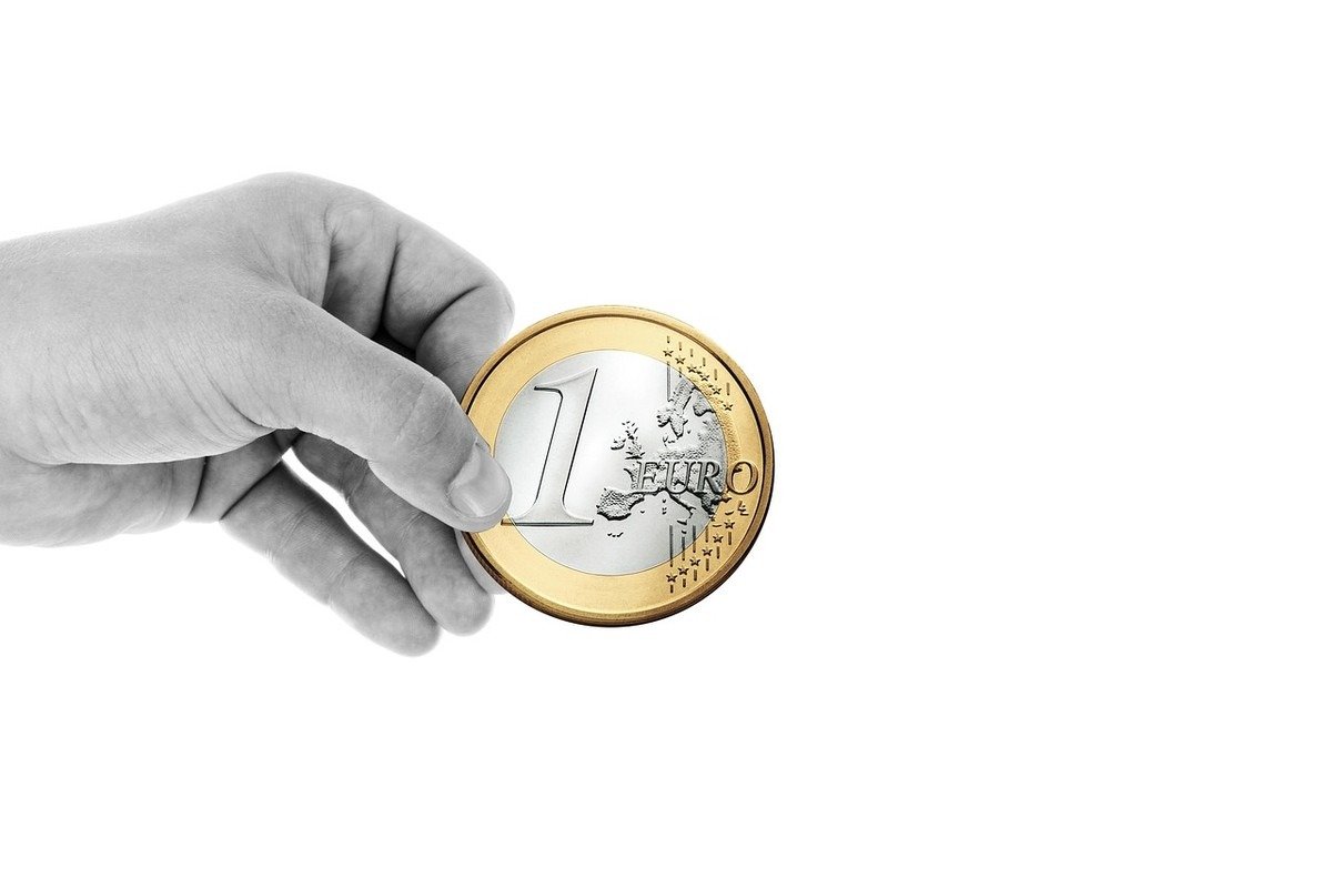 Main tenant une pièce de 1 euro avec face et revers visibles sur fond blanc Main tenant une pièce de 1 euro avec face et revers visibles sur fond blanc