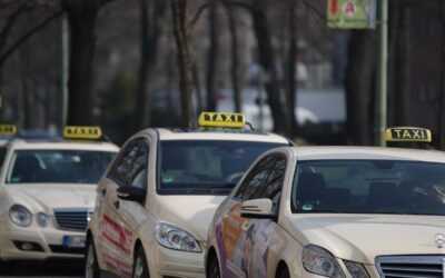 Des voitures-taxis alignées sur une rue, panneaux lumineux visibles