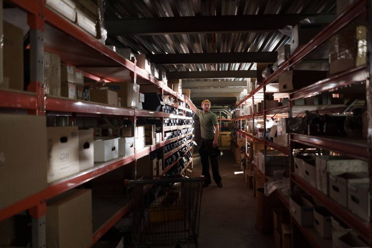 Homme debout dans un couloir d'entrepôt, entouré de rangées de boîtes et d'articles