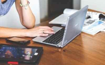 Une femme travaille sur ordinateur portable avec smartphone et tablette sur table en bois