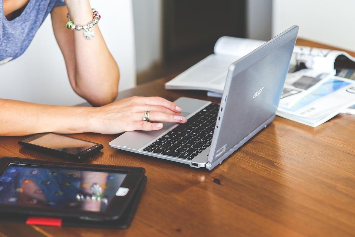 Une femme travaille sur ordinateur portable avec smartphone et tablette sur table en bois
