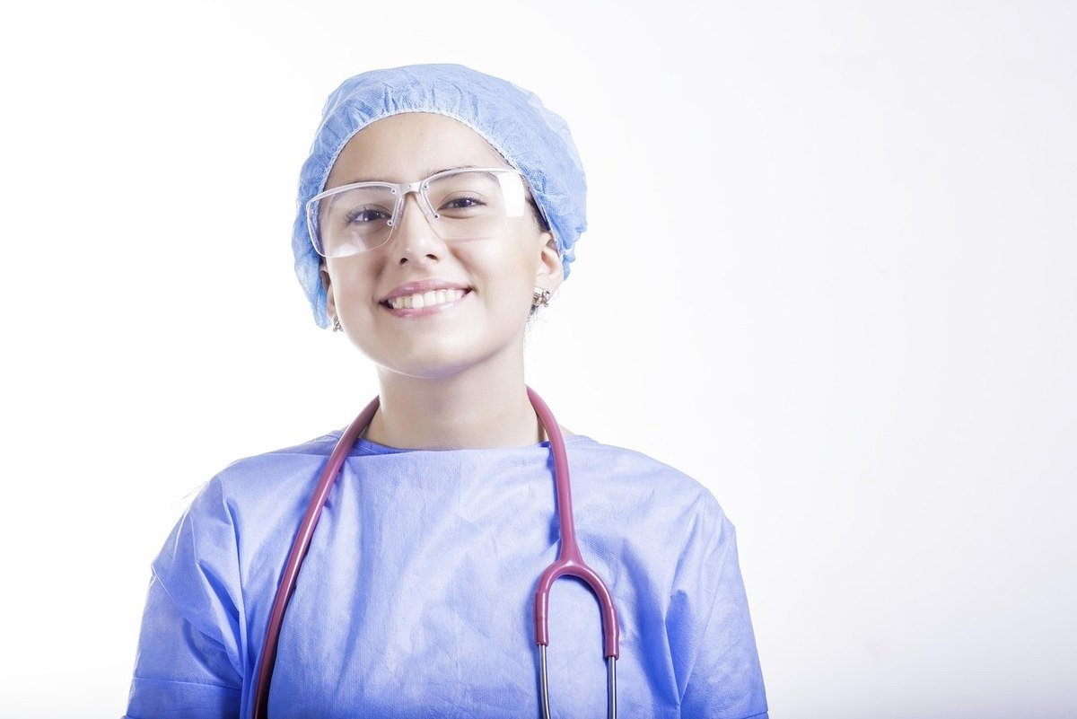 Professionnelle de santé en blouse bleue et bonnet chirurgical, stéthoscope autour du cou Professionnelle de santé en blouse bleue et bonnet chirurgical, stéthoscope autour du cou